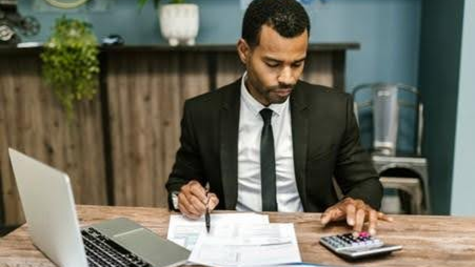 Man working on monthly accounting services with a laptop and calculator