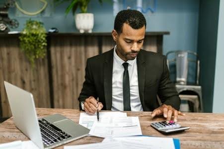 Man working on monthly accounting services with a laptop and calculator