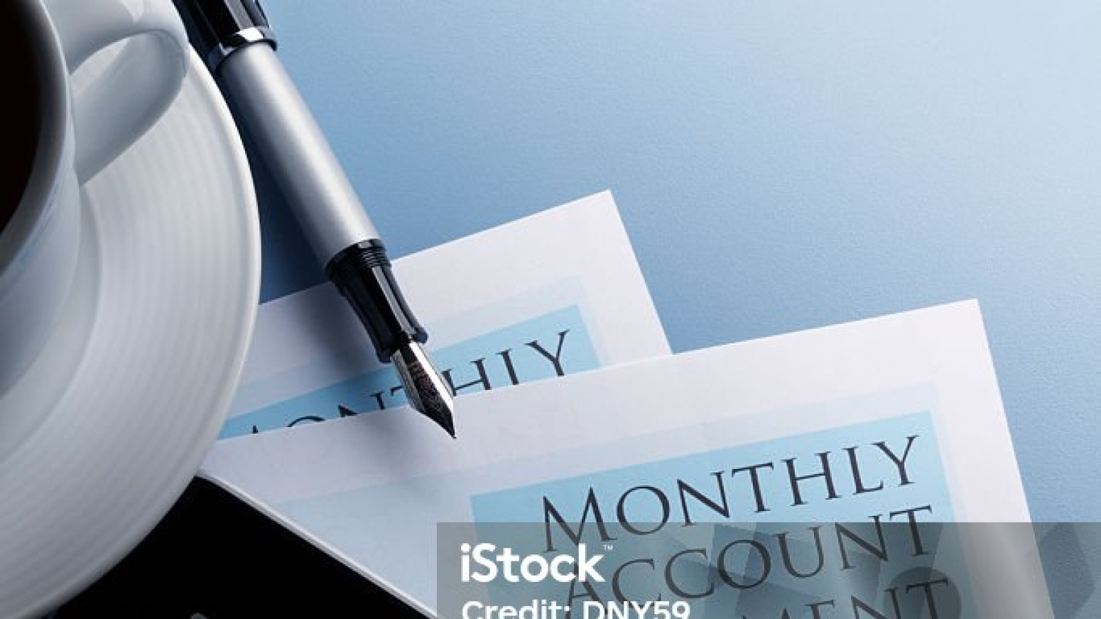 A vertical shot of a Monthly Account Statement document, a tablet displaying a financial graph, a pen, and a cup of coffee on a blue background.