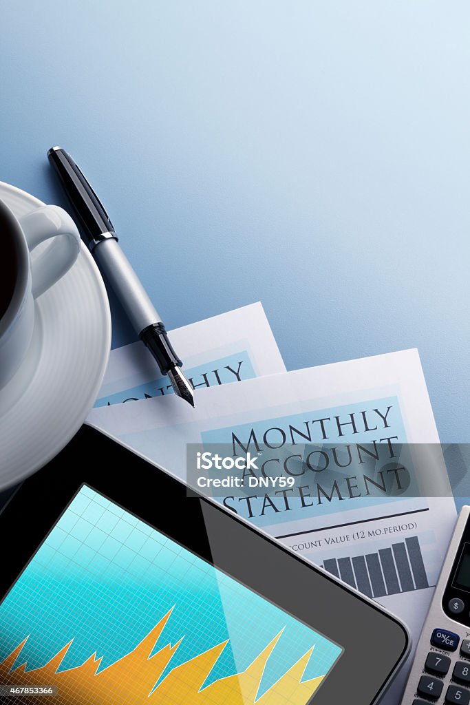 A vertical shot of a Monthly Account Statement document, a tablet displaying a financial graph, a pen, and a cup of coffee on a blue background.